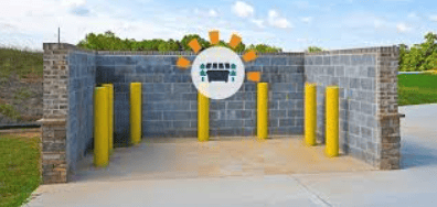 Concrete block waste enclosure with yellow bollards